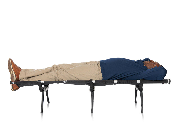 man laying on the set-up travel cot for hiking and camping